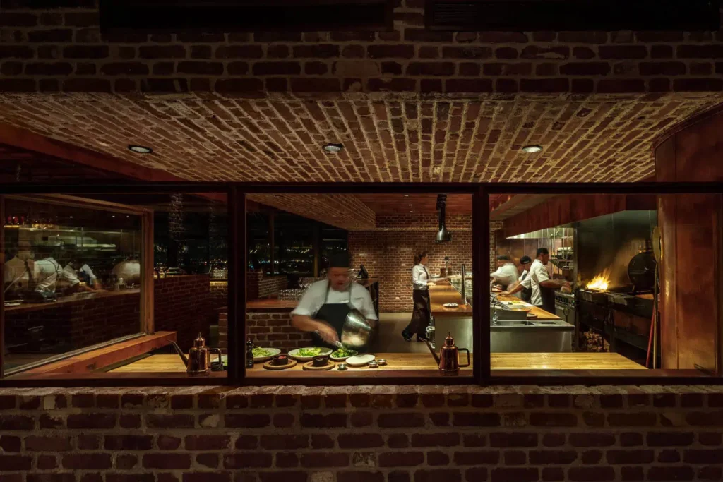 Sierra Restaurant interior at night with custom copper surfaces visible through the windows